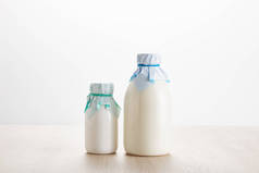 各种新鲜的有机奶制品，装在木制桌子上的瓶子中，与白色隔离