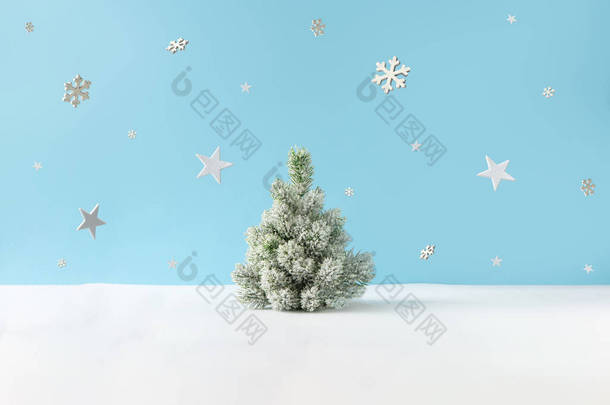 有白雪的圣诞树和明亮蓝色背景的雪花<strong>群星</strong>的创意布局。 最少的冬季自然假期场景.