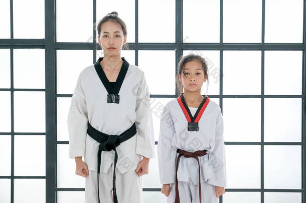 亚洲跆拳道教师和学生妇女和女孩站在讲台上，准备以跆拳道的一般姿态<strong>敬礼</strong>.