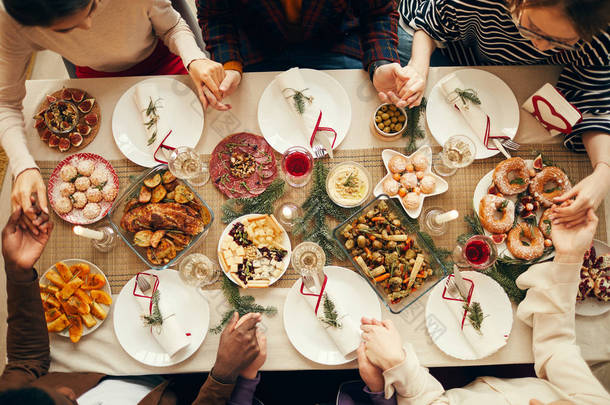 圣诞期间，一群人坐在餐桌前，手拉手祈祷，抄写空间，请看上图