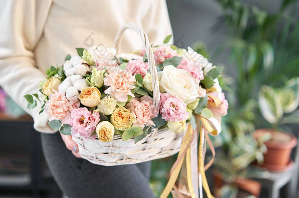 威克篮子中的花布置。美丽的花束混合花在女人的手。花卉店概念。漂亮的新鲜花束。鲜花递送