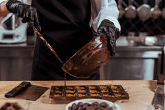 在把融化的巧克力倒入巧克力模子中的同时，用巧克力托着碗的剪影