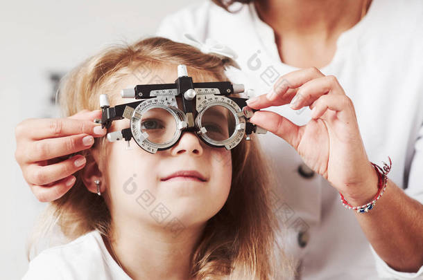 Difficult to see that <strong>word</strong>. Doctor checking little girl sight and tuning the phoropter.