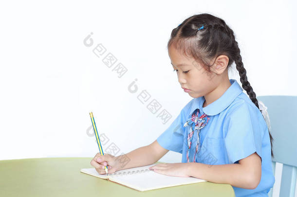 让穿着校服的小女孩在笔记本上写东西，<strong>书桌</strong>上的<strong>书桌</strong>被白色背景隔开了.