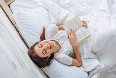 一个快乐的女孩躺在床上抱着书的头像