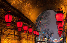 Xian, China - January 2018: Red lanterns and the Bell Tower of Xian illuminated by night seen from t