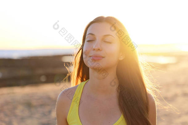 一名女子在早上日出时在海滩上呼吸新鲜空气的背光肖像