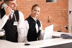 Male and female receptionists working at desk in hotel