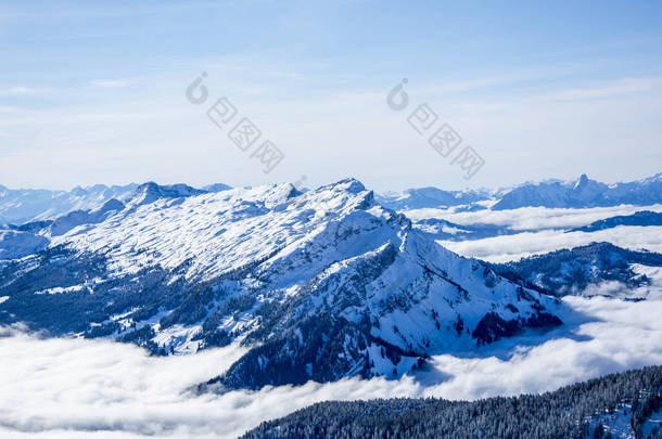 积雪覆盖了瑞士阿尔卑斯山的蓝山层。在阳光灿烂的日子里，天蓝色的，高山雪山的交汇处