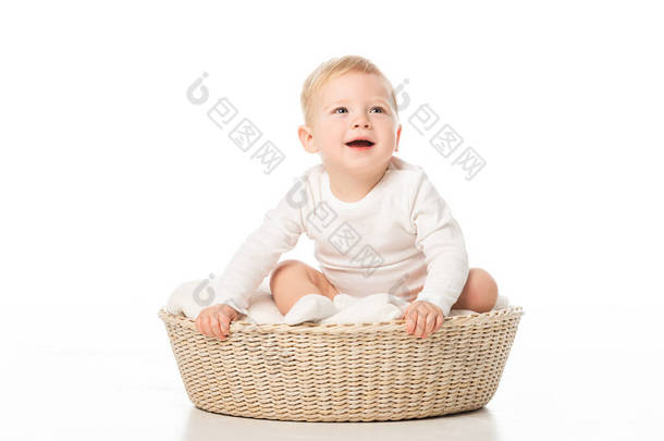 可爱的男孩，嘴张开，提着篮子，坐在里面的白色背景上