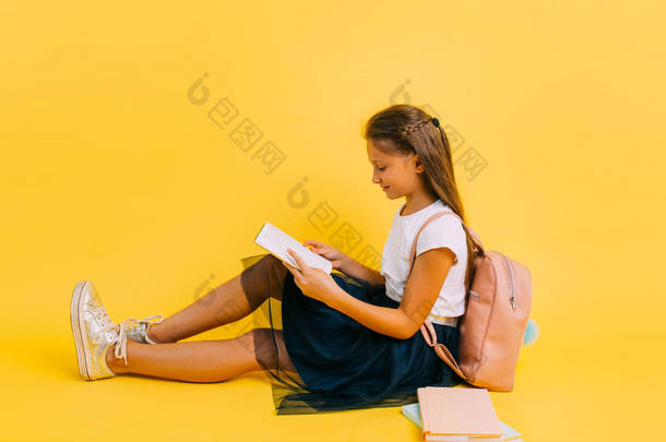 Smart teenage girl in school clothes doing homework reading a book