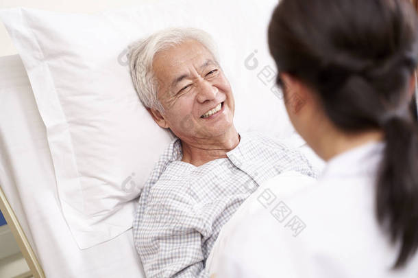 年轻的亚洲医生在临终关怀的<strong>病床</strong>边与老年病人交谈