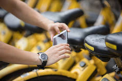 城市中使用智能手机和扫描共享自行车Qr代码的妇女的手