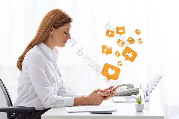 商业女性使用智能手机接近文件和笔记本电脑的侧面视图，社交媒体图解