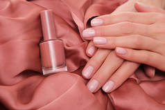 美丽的女性手，有着精致、自然的修指甲，躺在缎子上。漂亮的浅粉色泽.