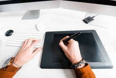 数码设计师在桌面上使用图形平板电脑键盘的截图