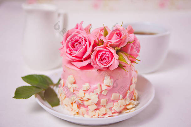 有<strong>粉色</strong>釉料的小蛋糕，漂亮的玫瑰，一杯咖啡，白桌子上的<strong>礼品盒</strong>