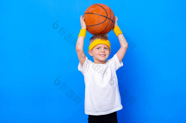 一个身材矮小的小男孩,背负着蓝色工作室背景的<strong>篮球</strong>运动.体操运动。<strong>儿童</strong>运动员。活动。体育。健康、健康和精力。成功