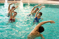 在游泳池的水上运动中，教练与面带微笑的人一起锻炼