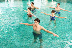 在游泳池进行水上健美操时，教练与年轻人一起练习的高视角视角