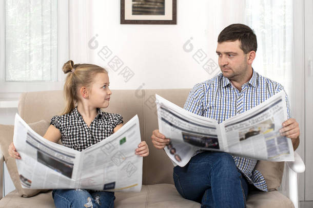 杀了一个女儿和爸爸一起呆在家里他们坐在沙发上，用同样的方式一起<strong>看报</strong>纸。女儿模仿她的父亲.