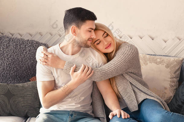 Happy man and woman embracing on sofa in living room