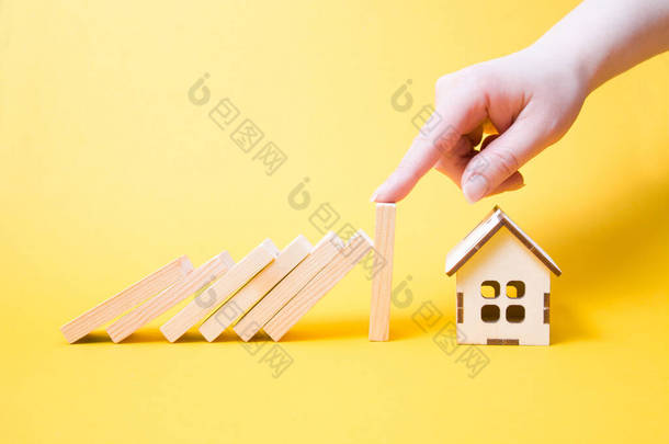停止<strong>掉落</strong>木制多米诺骨牌<strong>掉落</strong>房屋模型，房地产保护概念，黄色背景，复制位置，财产保险概念