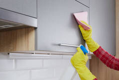 做清洁厨房的女人用粉色抹布和洗涤剂在厨房里洗黄色手套。清扫房屋