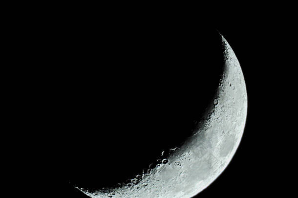 在漆黑的夜空中，有越来越多的镰状四分之一的月亮和它的<strong>月球陨石</strong>坑
