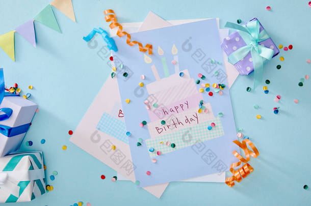 蓝色背景的礼品盒和生日贺卡附近彩色彩斑斓的五彩纸屑的顶部视图