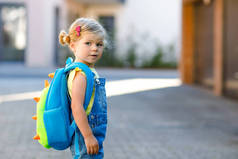 可爱的小女孩在第一天上学的时候就很可爱。健康漂亮的婴儿步行去幼儿园和幼儿园。快乐的孩子，背着背包在街上，户外.