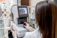 近照，现代诊所的女医生用特殊的光学仪器检测病人的眼睛.