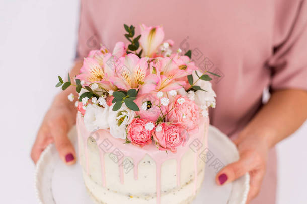 <strong>紧紧</strong>抓住女人的手，手里拿着一个装饰着白底花的蛋糕.