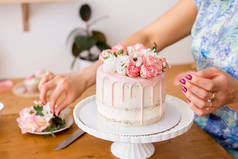 用鲜花装饰蛋糕的女性小手的特写.