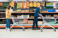 在检疫期间，一名男子与一名女子在超级市场购买购物车.
