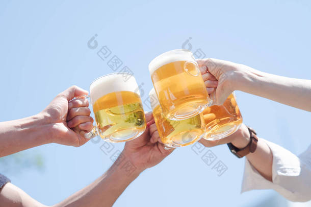 四个男人和女人手拿着啤酒在蓝天下敬酒