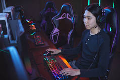 亚洲年轻人在网络游戏椅上玩电子游戏的高角肖像画，复制空间