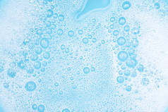 水面上有气泡的特写白色泡沫，用肥皂和蓝色浴池洗涤粉末，抽象的背景透明泡沫.