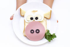 三明治公牛。小孩子的手有一个白色的盘子，上面夹着三明治当早餐或午餐.