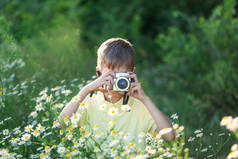 带着专业相机的孩子们正在阳光灿烂的夏日拍摄大自然的花朵。小孩在迷迭香花地拍照.