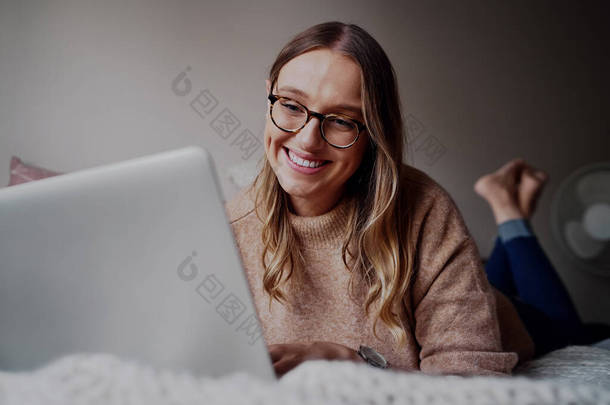 一个快乐的年轻女商人在家里卧室里的笔记本<strong>电脑</strong>上工作的肖像- -<strong>学生们</strong>正在上新的在线课程
