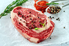 生鲜的、大理石状的牛肉牛扒，在白色牛皮纸上加入调味品。有机鲜肉的概念