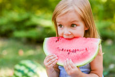 孩子们在花园里吃西瓜。孩子们在户外吃水果。儿童健康小吃。2岁的小女孩在吃西瓜