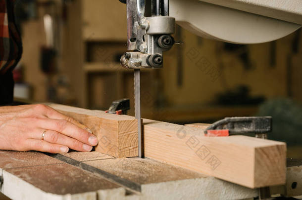 在木工车间工作的过程穿工作服的人在木工车间锯成的带子上工作。职业、木工、木匠和人的概念