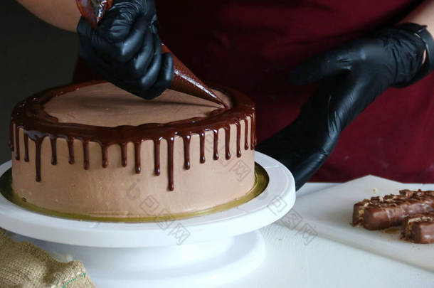 糖果店加工桌上的巧克力<strong>蛋糕</strong>。用液体巧克力装饰<strong>蛋糕</strong>的过程.在深色背景下<strong>制作</strong>巧克力<strong>蛋糕</strong>的过程