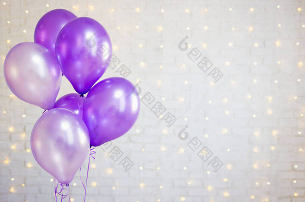 党的概念- -白色砖墙背景上的紫色气球，有灯光