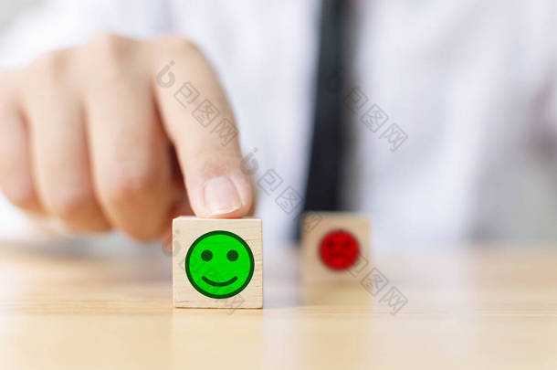 实业家的手在木块立方上选择笑脸，最佳优秀的业务服务评价客户体验，<strong>满意度调查</strong>概念