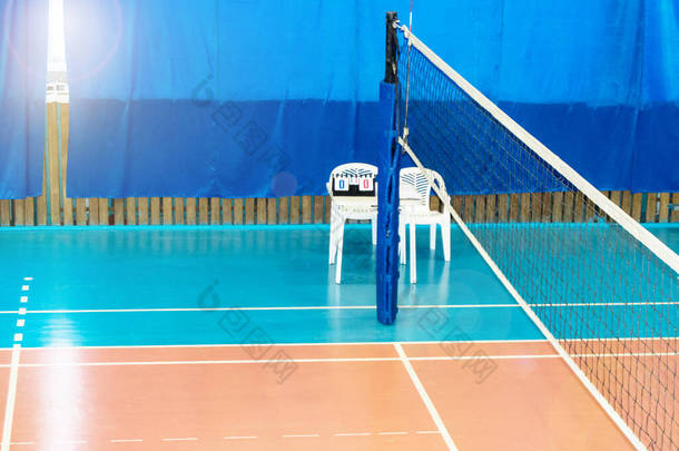现代空荡荡的学校体育馆室内排球网，裁判椅和记分板.