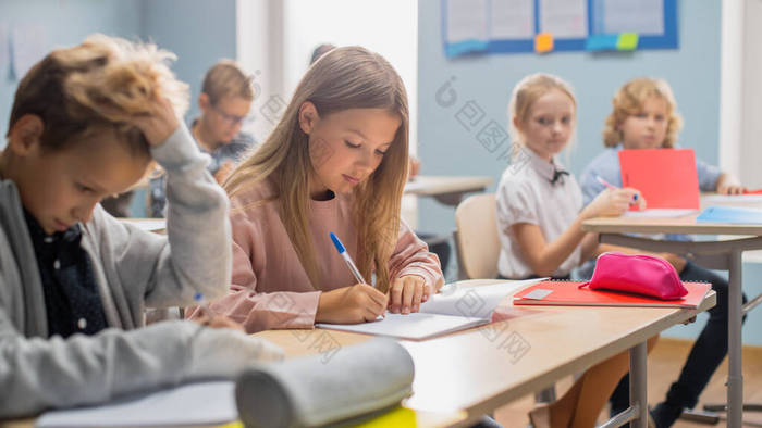 不同儿童的小学课堂认真听老师讲课。在学校里聪明的孩子们在练习本上写作，参加考试和考试。儿童学习