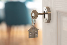 打开新家的大门。门把手与钥匙和家庭形状的钥匙链。抵押贷款、投资、房地产、财产和新住房概念
